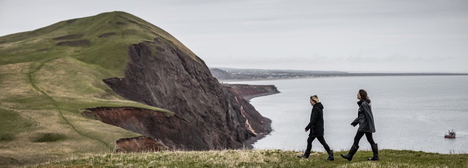 Deux amies marchent dans le paysage des Îles de la Madeleine par temps gris