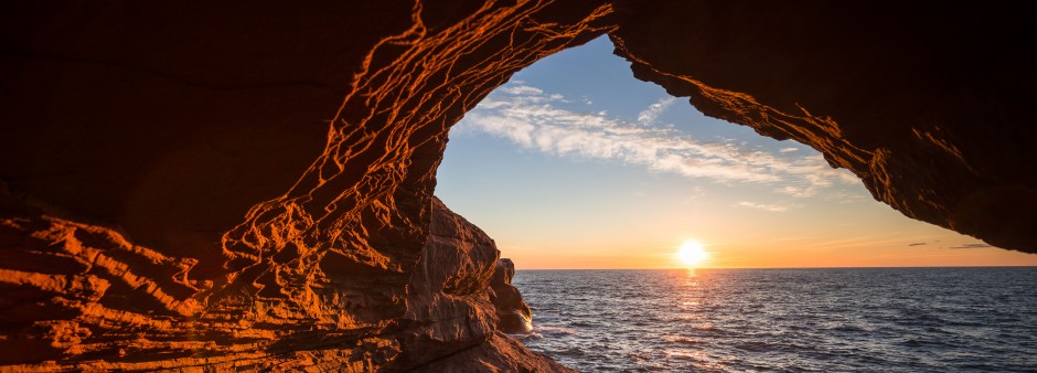 Le lever de soleil dans le trou d'une falaise de grès rouge aux îles de la Madeleine