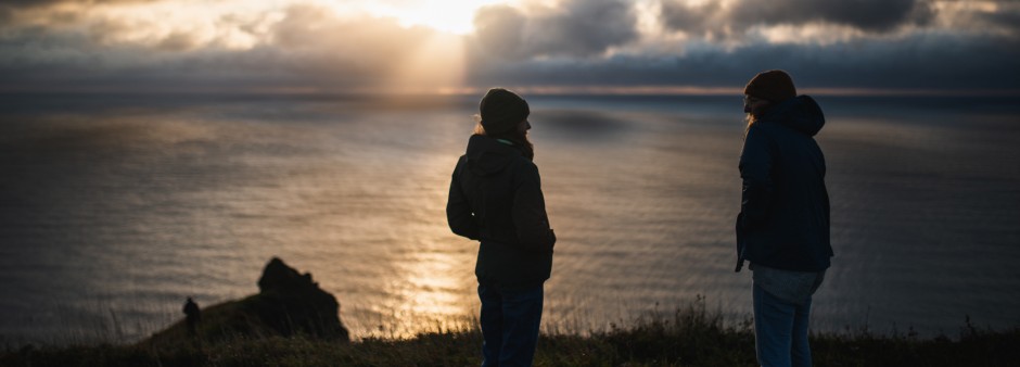 Two people admire a sunset near the cliffs in the Îles de la Madeleine