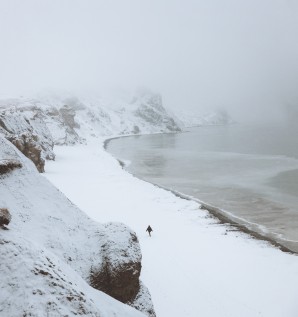 A person walking along a snow-covered beach
