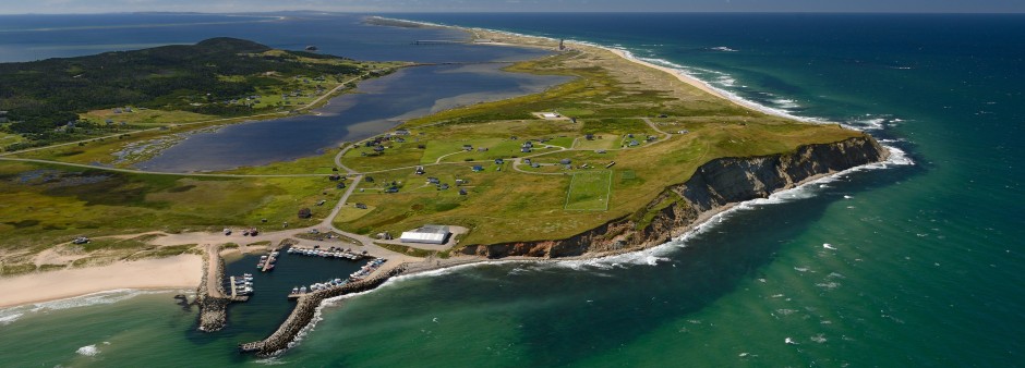 Vue aérienne de Grosse Île aux Îles de la Madeleine avec falaises, port de pêche et plages s'étendant le long du golfe du Saint-Laurent.