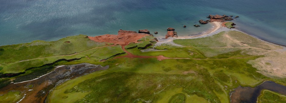 Vue de l'île de la Grande Entrée aux Îles de la Madeleine, avec ses falaises rouges, ses plages et ses prairies côtières.