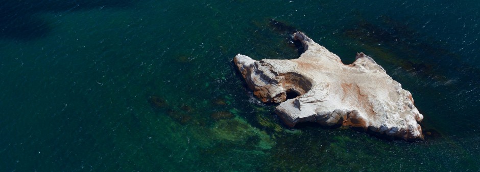 Un îlot rocheux des Îles de la Madeleine, entouré d'eau turquoise du golfe du Saint-Laurent