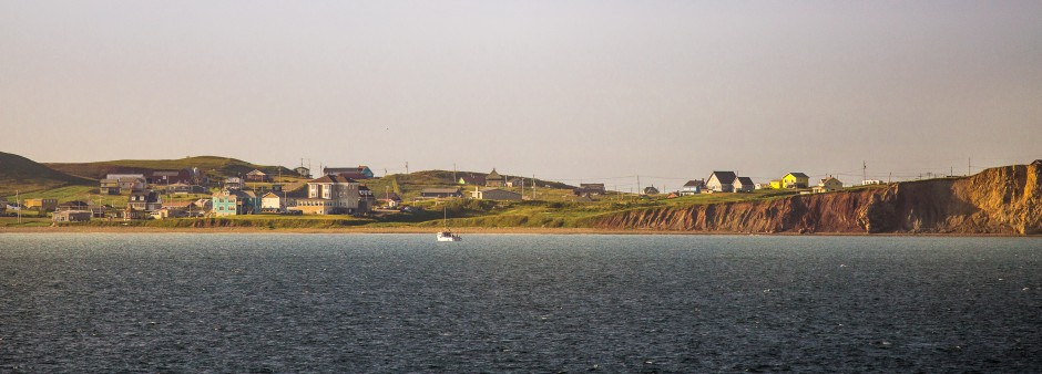 Village côtier des Îles de la Madeleine au bord des falaises rouges, avec maisons colorées et vue sur le golfe du Saint-Laurent.